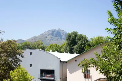 a white building with a mountain in the background at The Xrossing - free parking in Stellenbosch