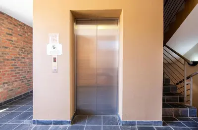 a metal elevator in a building with a brick wall at The Xrossing - free parking in Stellenbosch