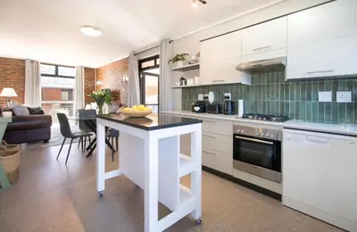 a kitchen with white cabinets and a black counter top at The Xrossing - free parking in Stellenbosch