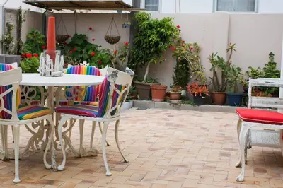 a table and chairs on a patio with plants at 5 Lantra in Strand