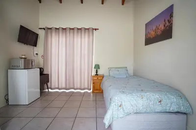 a bedroom with a bed and a refrigerator in it at Ocean Vibes in Cape Town