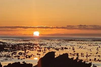 a group of people on the beach at sunset at Hermanus Sea view room in Hermanus