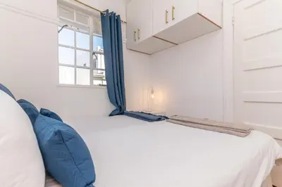 a bedroom with a bed with blue pillows and a window at Secure and Modern 2Bed Apartment in Cape Towns Charming Rondebosch in Cape Town