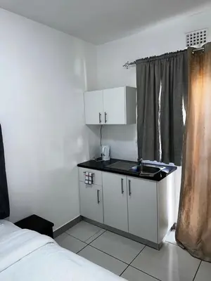 a kitchen with a sink and a bed in a room at Beatrice Guesthouse in Cape Town