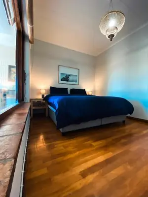 a bedroom with a blue bed and a wooden floor at The Salty Surf Shack in Cape Town