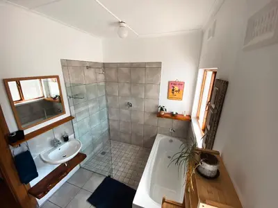 a bathroom with a shower and a sink and a tub at The Salty Surf Shack in Cape Town