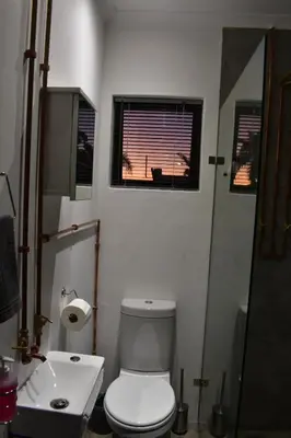 a bathroom with a toilet and a sink and a window at Langbeentjie Inn Two Point O in Cape Town