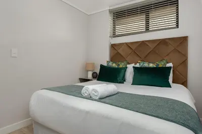 a bedroom with a large white bed with green pillows at Burmeister on Park 007 in Cape Town