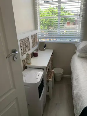 a small bedroom with a bed and a desk with a window at The Lazy Expat - Paarl - Self Catering Apartment in Paarl