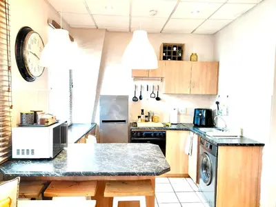 a kitchen with wooden cabinets and a counter top at The Skinny Expat - Paarl - Self Catering Apartment in Paarl