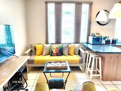 a living room with a yellow couch in a kitchen at The Skinny Expat - Paarl - Self Catering Apartment in Paarl