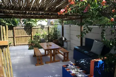 a patio with a table and a bench and a pergola at A spacious Haven near Bloubergstrand beach in Cape Town