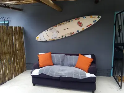 a surfboard hanging on a wall next to a couch at A spacious Haven near Bloubergstrand beach in Cape Town