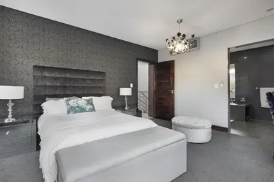 a bedroom with a large white bed and a chandelier at Baronetcy Kings Villa in Plattekloof