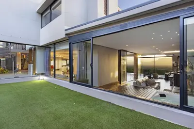 an open living room with large windows and green grass at Baronetcy Kings Villa in Plattekloof