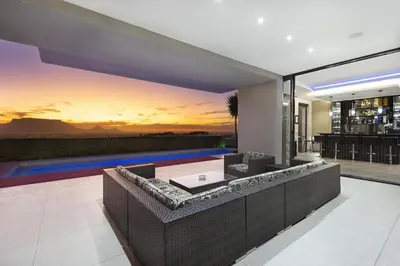 an open living room with a sunset mural on the wall at Baronetcy Kings Villa in Plattekloof