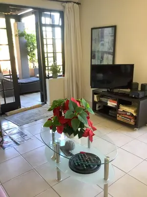 a living room with a glass table with flowers on it at Cozy Garden apartment with amazing view in Cape Town