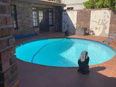 a toy robot sitting next to a swimming pool at Cozy Garden apartment with amazing view in Cape Town
