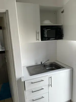a small kitchen with a sink and a microwave at Beatrice Guesthouse in Cape Town