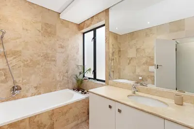 a bathroom with a tub and a sink and a mirror at Sunset Kite & Golf Villa in Cape Town