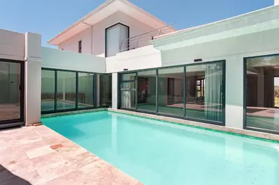 a swimming pool in front of a house at Sunset Kite & Golf Villa in Cape Town