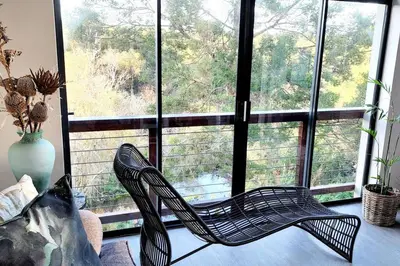 a chair in front of a window in a room at 4 Bed Selfcatering River Tree House overlooking the Onrus river in Hermanus