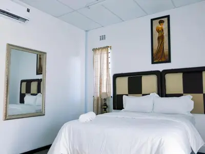 a white bedroom with a large bed and a mirror at 33 Goulborn street Goodwood in Cape Town
