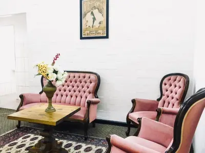 two pink chairs and a table with a vase of flowers at 33 Goulborn street Goodwood in Cape Town