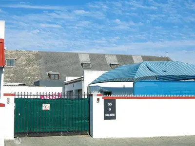 a building with a green gate and a building with a roof at 33 Goulborn street Goodwood in Cape Town