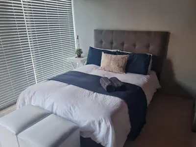 a bedroom with a large bed with blue pillows at La Maison Kuilsrivier in Cape Town