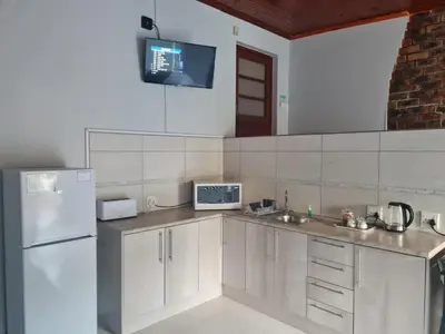 a kitchen with white cabinets and a white refrigerator at La Maison Kuilsrivier in Cape Town