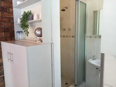 a bathroom with a shower and a white refrigerator at La Maison Kuilsrivier in Cape Town