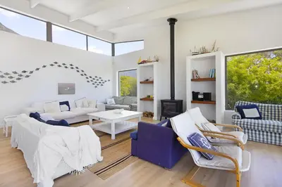 a living room with blue and white furniture and windows at Suidersee-Voelklip in Hermanus