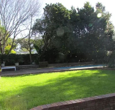 a park with a green lawn with benches and trees at Lovely 1-bedroom rental with a pool in Cape Town