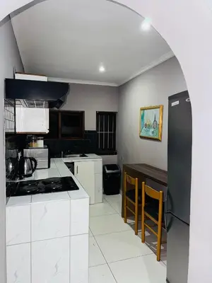 a kitchen with white cabinets and a black refrigerator at Mila Lodge 1 in Cape Town