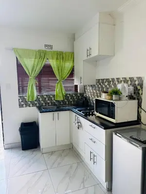 a kitchen with white cabinets and a microwave at Mila Lodge 2 in Cape Town