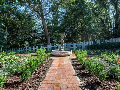a garden with a fountain in the middle of a fence at Devon Castle Forest Lodge in Stellenbosch