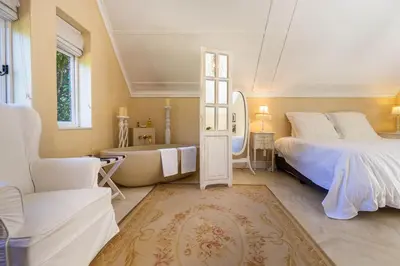 a bedroom with a bed and a tub and a sink at Devon Castle Forest Lodge in Stellenbosch