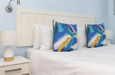 a bed with white sheets and blue pillows at Pips Place 301 in Strand