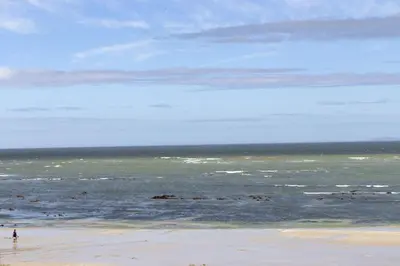 a beach with a person standing in the ocean at Pips Place 301 in Strand
