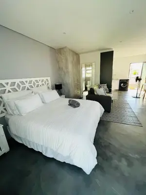 a bedroom with a large white bed and a living room at Sleepy Tides in Cape Town