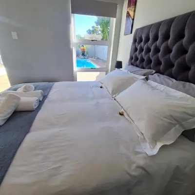 a bed with white pillows and a headboard and a window at 51 On Vlei in Cape Town
