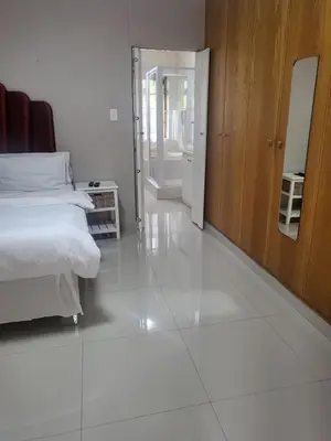 a bedroom with a bed and a large white floor at MJ's Guest House in Cape Town