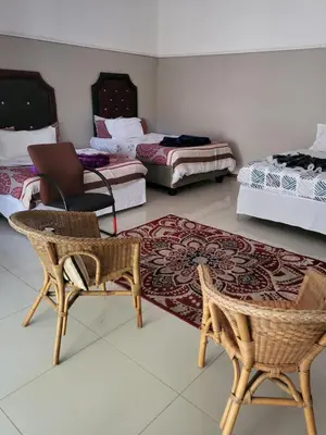 a room with two beds and a chair and a rug at MJ's Guest House in Cape Town