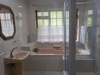 a bathroom with a bath tub and a sink at MJ's Guest House in Cape Town