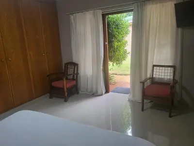 a bedroom with two chairs and a large window at MJ's Guest House in Cape Town
