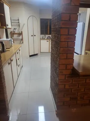 a kitchen with a brick wall and a white floor at MJ's Guest House in Cape Town
