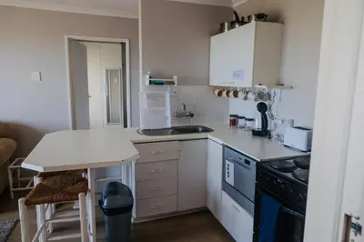a kitchen with white cabinets and a counter top at Ocean Breeze @ Hermanus Beach Club in Hermanus