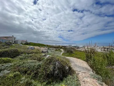 a path on a beach with a house and the ocean at Ocean Breeze @ Hermanus Beach Club in Hermanus