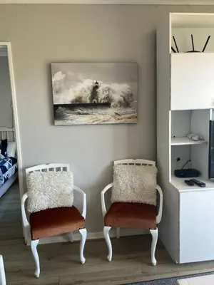a room with two chairs and a painting on the wall at Ocean Breeze @ Hermanus Beach Club in Hermanus